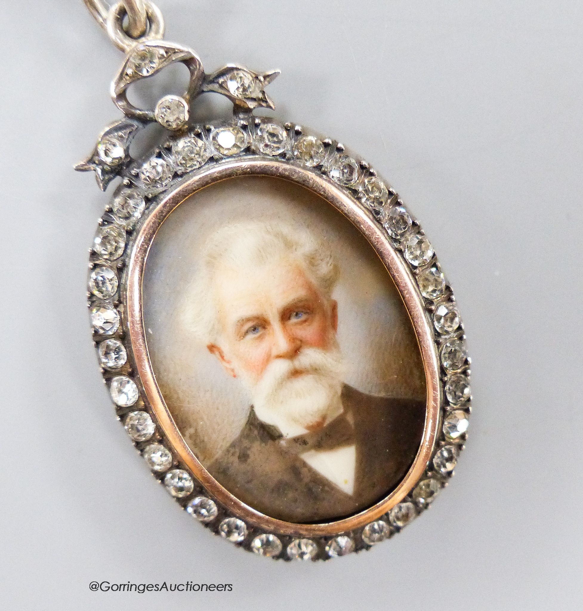 A late 19th century 900 standard gilt white metal and paste set oval pendant locket, inset with portrait of a gentleman, 42mm.